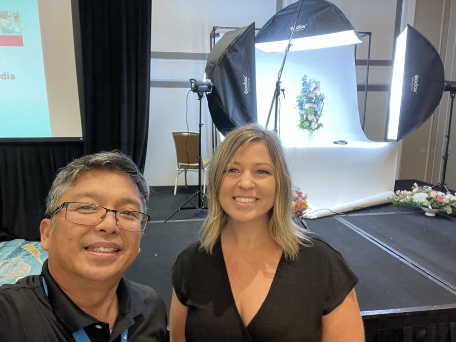 Renato Cruz Sogueco with a colleague beside a floral photography studio set up at an industry event